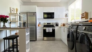 A modern kitchen with white cabinets, stainless steel appliances, and a tiled floor. - Sea Breeze Tunnel Hideaway 3 (Quebradillas)