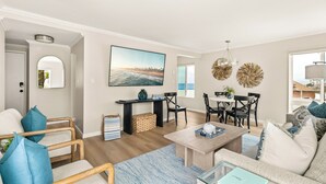 A modern living room with a wooden coffee table, a sofa, and a dining area with a table and chairs. - Seize the Day by Gather: 2BR Retreat w/ Views & Parking (La Jolla)