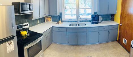 Enjoy cooking in this kitchen with a microwave and oven, a large window offering a view of the outdoors.