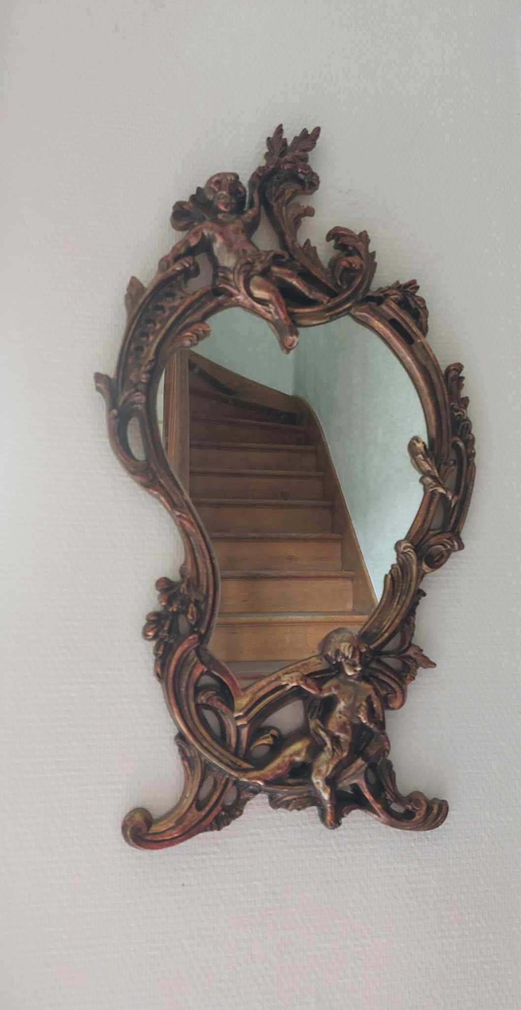 Un espejo con un marco decorativo fijado a la pared.