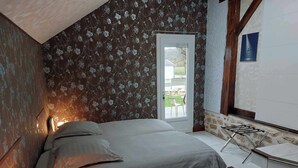 A bedroom with a bed, a nightstand, a lamp, a window with a view of the outdoors, and a staircase leading to an upper level.