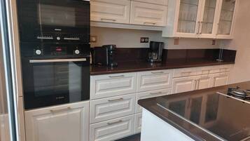 A modern kitchen with white cabinetry, a Bosch oven, and a coffee maker.