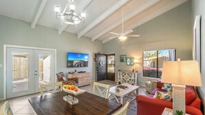 A spacious living room with a wooden dining table, a red sofa, and a ceiling fan.