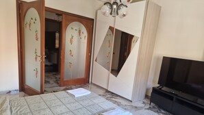 A bedroom with a bed, a TV, a wardrobe with mirrors, and a door leading to another room. - ROYAL HOUSE APPARTMENT DELUXE close to the main services and the sea. (Civitavecchia)