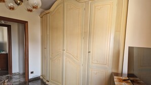 A spacious room with a large wardrobe, a marble floor, and a bed with a floral bedspread. - ROYAL HOUSE APPARTMENT DELUXE close to the main services and the sea. (Civitavecchia)