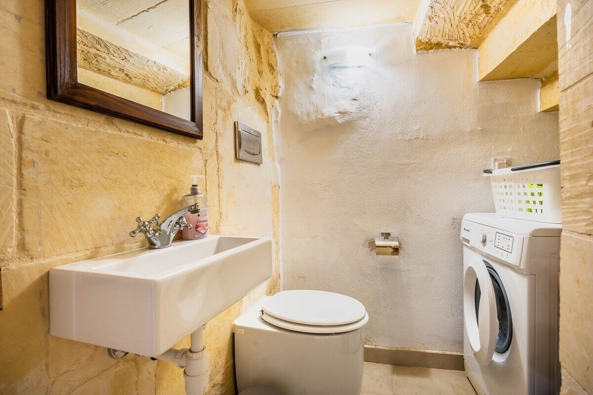 A compact bathroom with a sink, toilet, and washing machine.