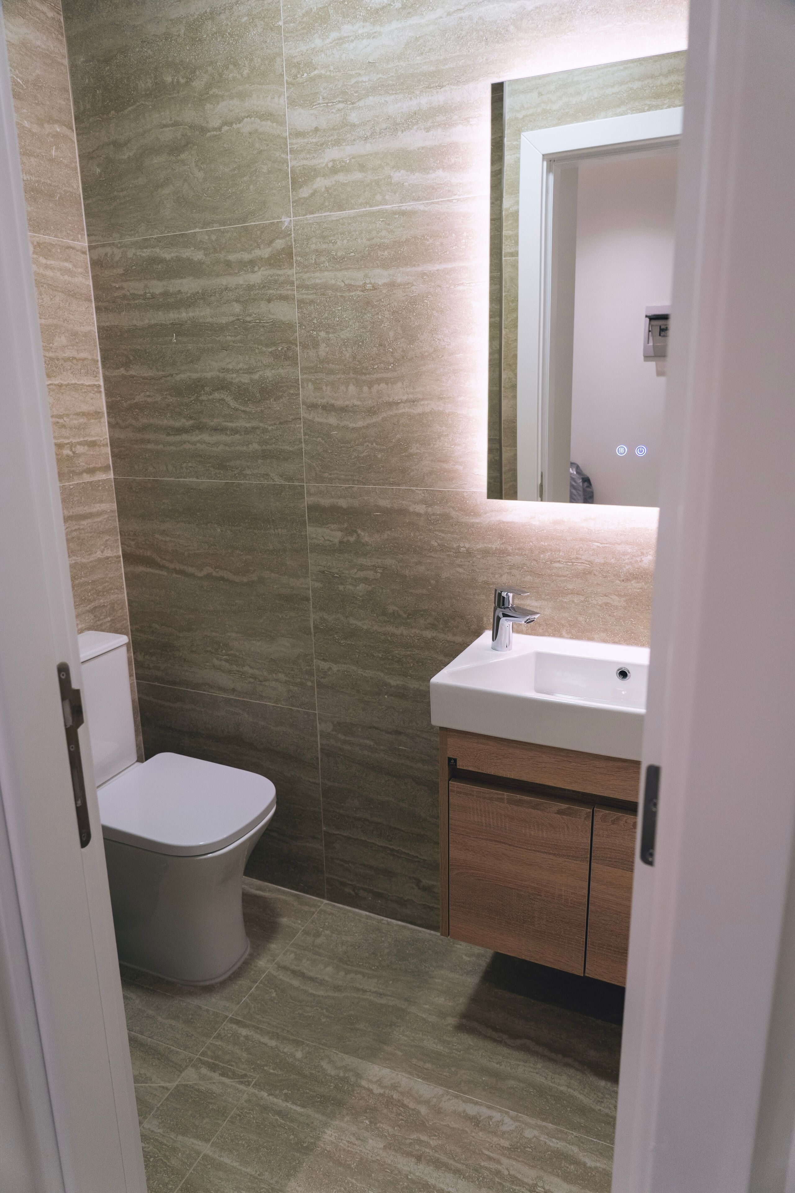 A bathroom with a toilet, sink, and wooden cabinet.