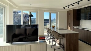A modern kitchen with a large island, bar stools, and a flat-screen TV.