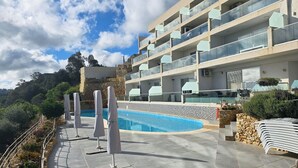 Een modern hotel met een zwembad, terras en uitzicht op het omliggende landschap.