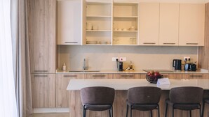 Een moderne keuken met een centraal eiland, barkrukken en een bank.