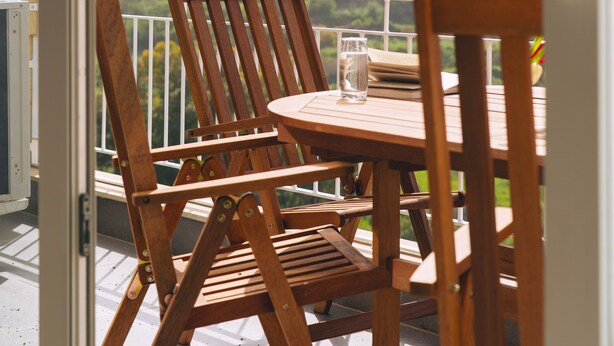 Un balcon avec des chaises et une table en bois, offrant une vue sur le paysage urbain et ses bâtiments historiques.