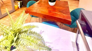 Ein Wohnzimmer mit Holztisch, einer Couch, einem Fernseher und einer Topfpflanze.