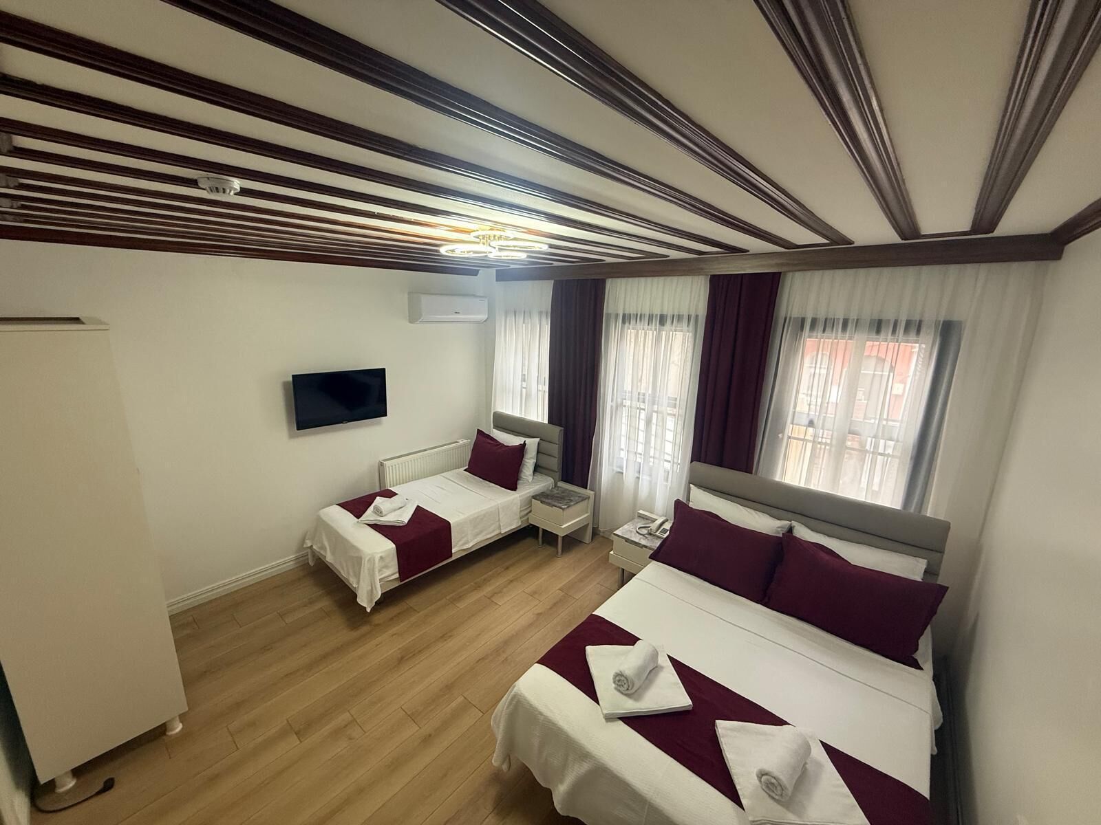 Ein Hotelzimmer mit zwei Betten, einem Fernseher und einem Fenster mit Vorhängen.
