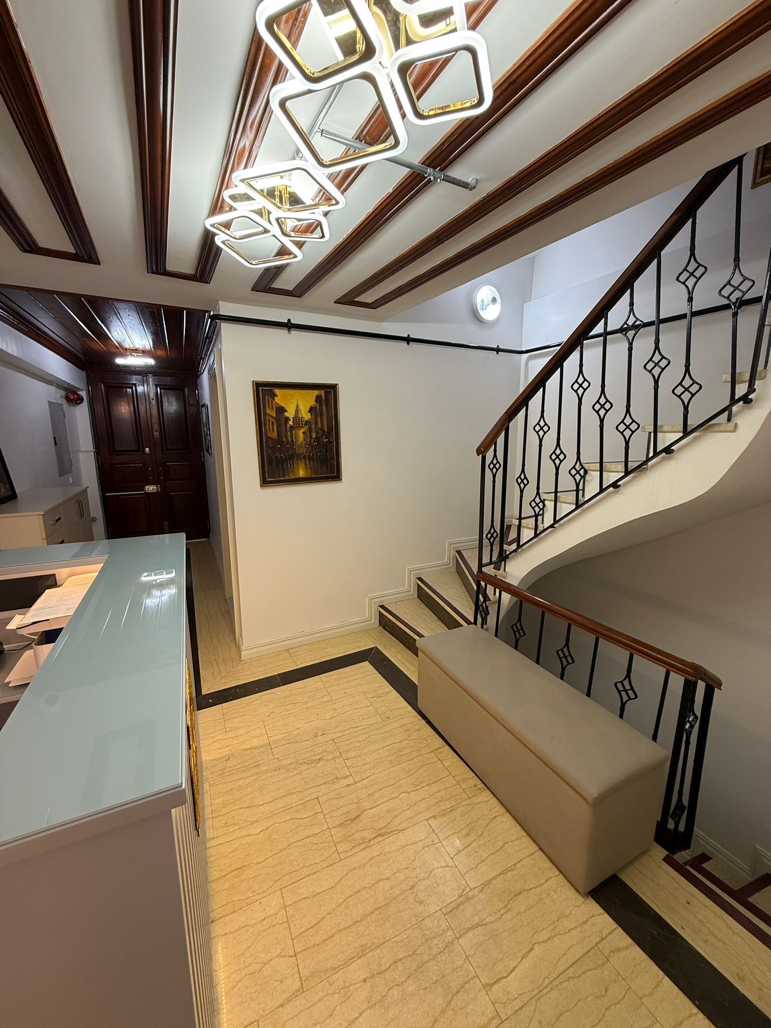 A staircase with a wooden handrail and black metal balusters, leading to an upper floor.