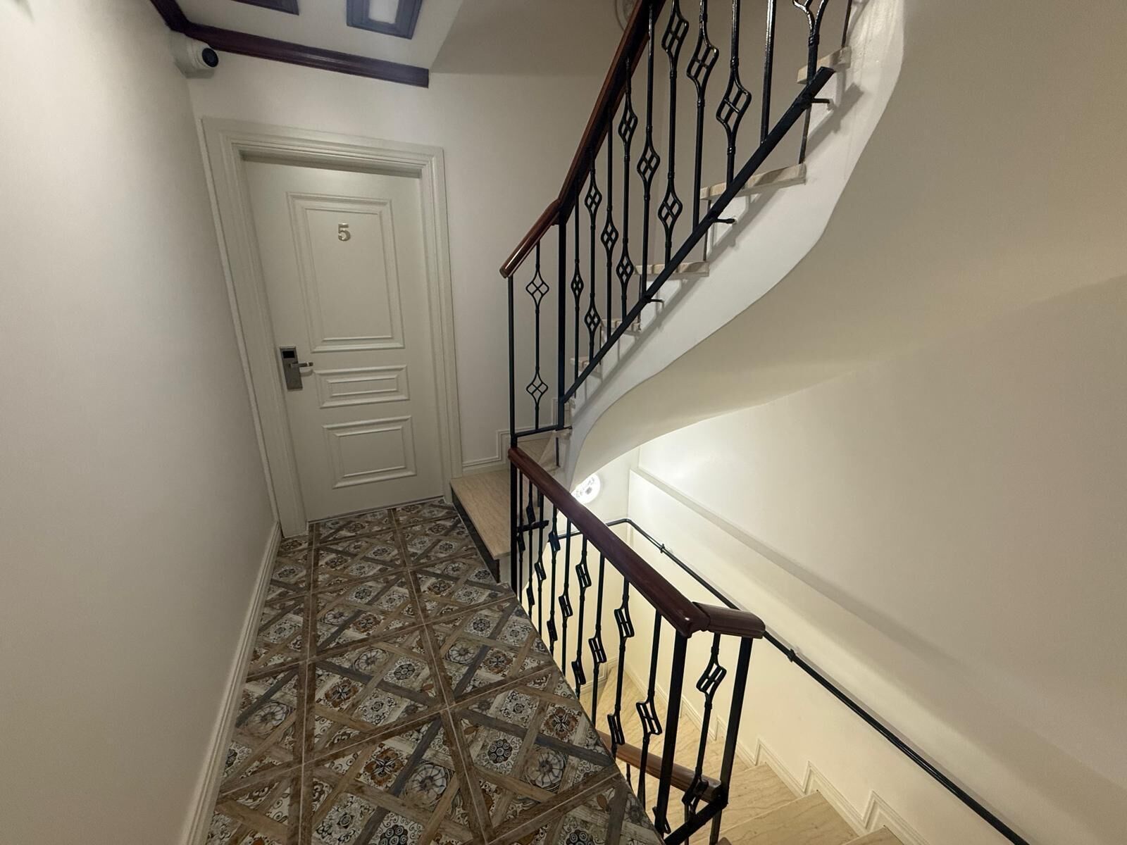A staircase with a patterned floor and a white door with the number 5.