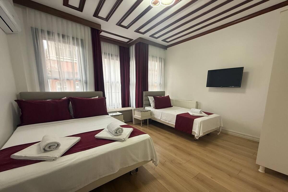 A hotel room with two beds, a TV, and a window with curtains.