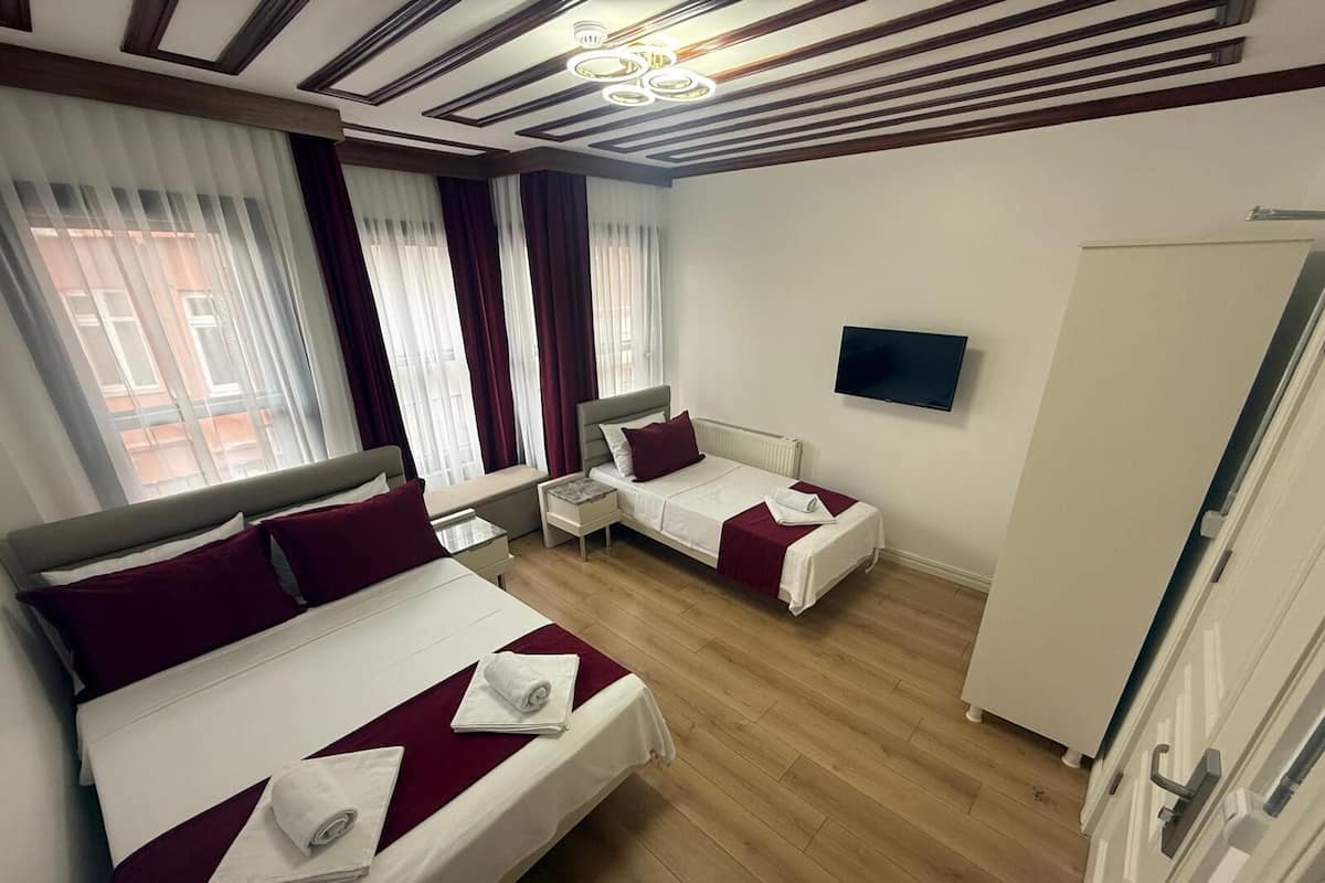 A hotel room with two beds, a TV, and a wardrobe.