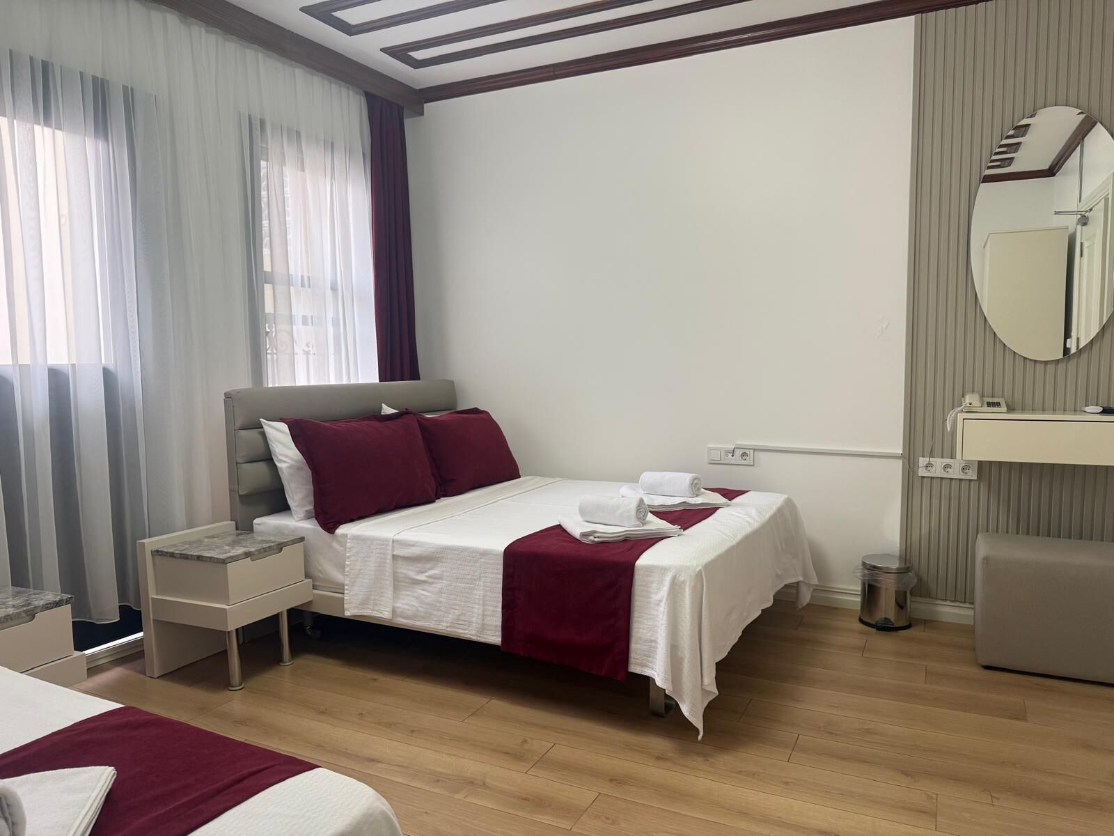 A hotel room with a bed, bedside table, and a mirror.