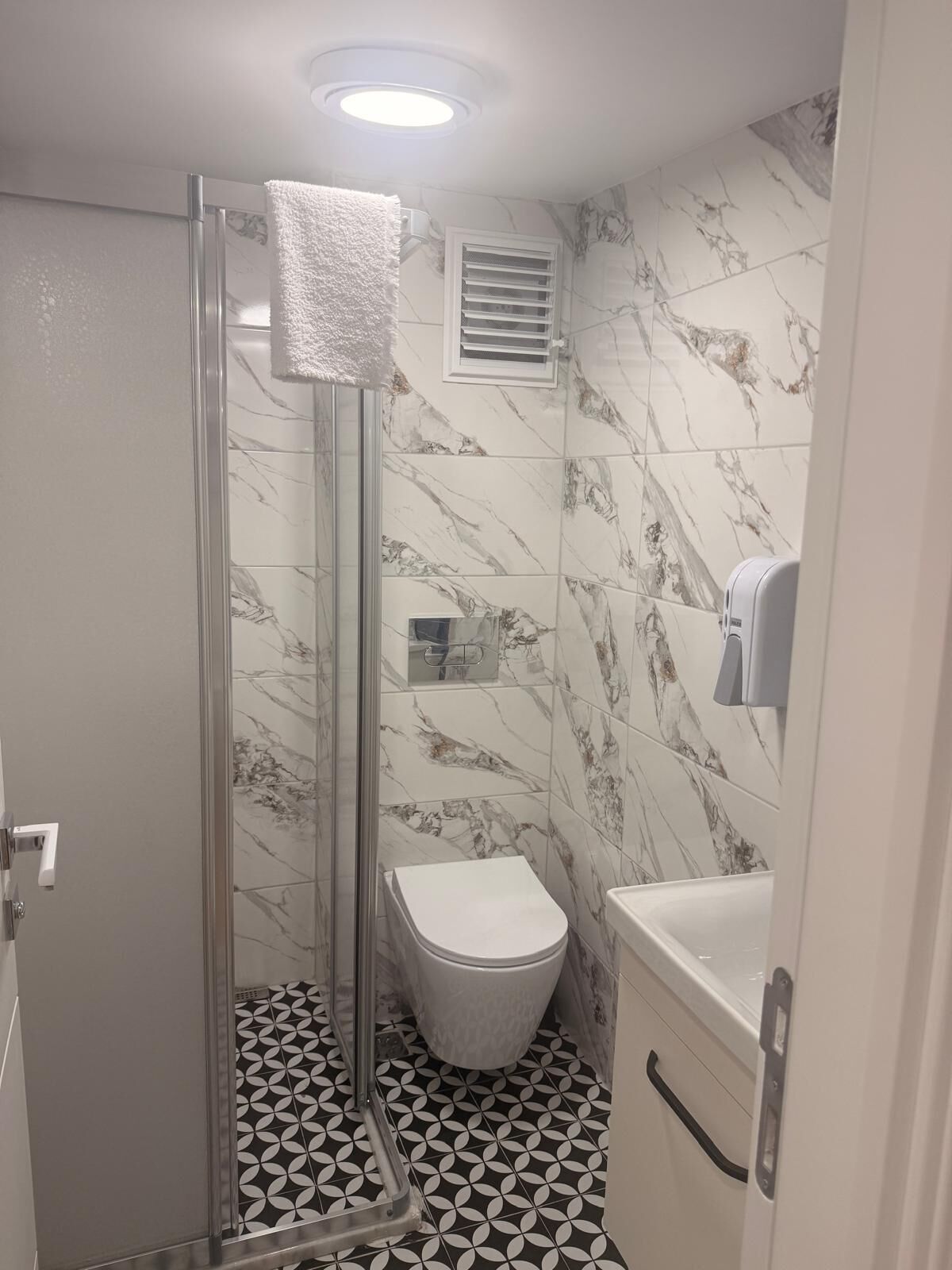 A bathroom with a glass-enclosed shower, a toilet, and a sink.