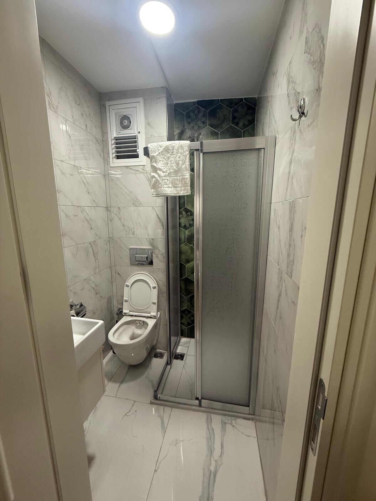 Une salle de bain avec des toilettes, un lavabo et une douche.