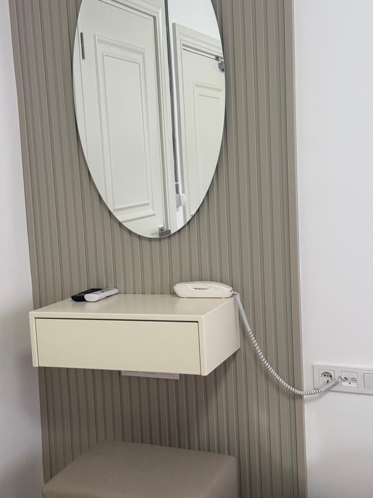 Un tocador de baño con espejo, teléfono y toalla.