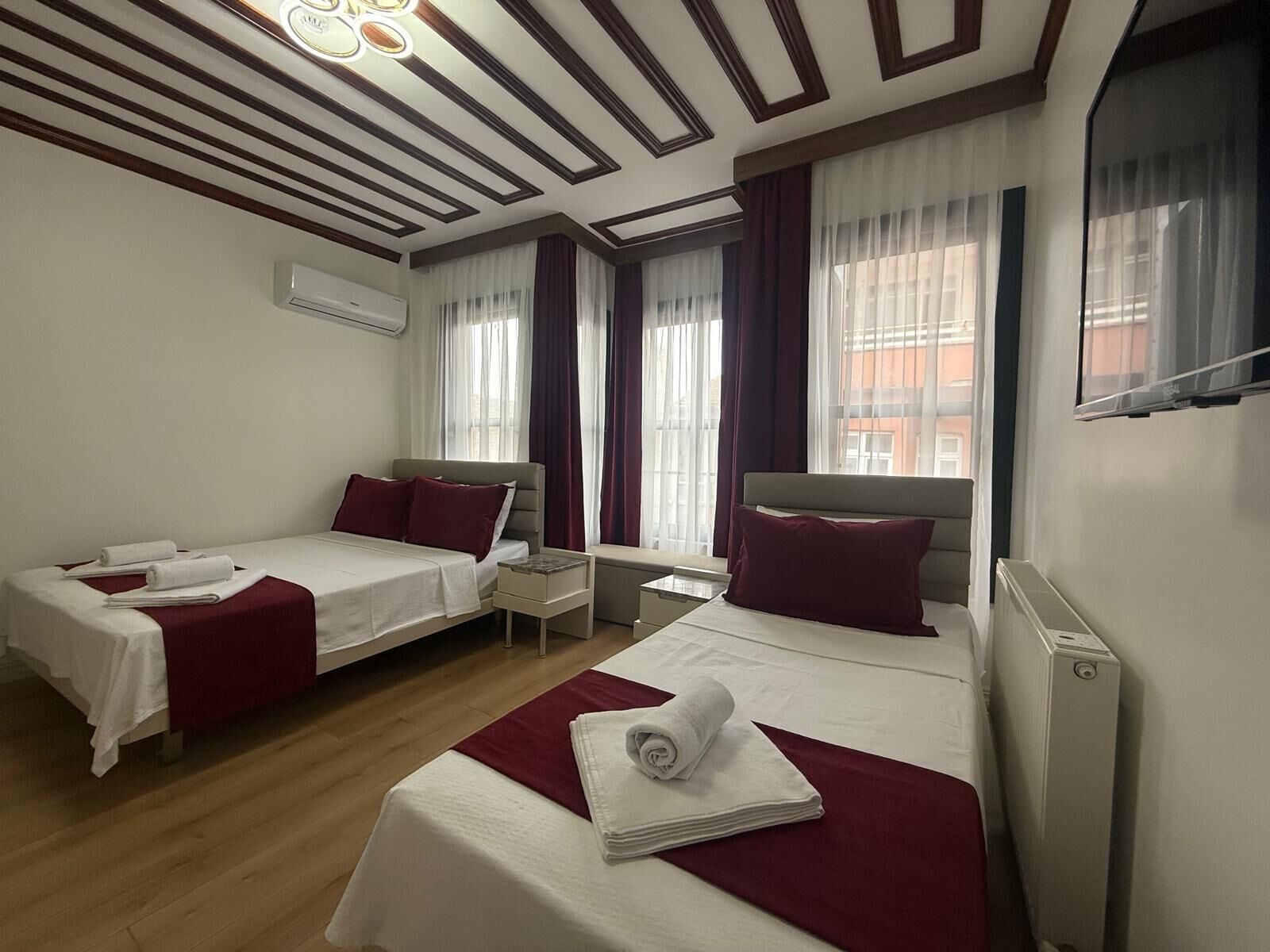 A hotel room with two beds, a TV, and a window with curtains.