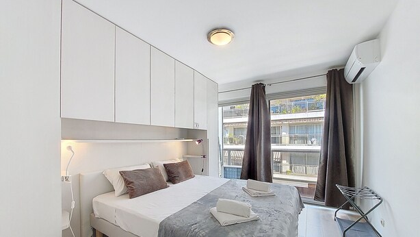 A modern bedroom with a bed, bedside lamp, and a view of a balcony with curtains. - N&J - CLEA - Terrace - Central (Niza)