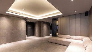 A modern lobby with a large sectional sofa, recessed lighting, and a polished stone floor. - Scarlatti Hotel Milano (Milan)