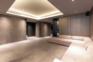 Um lobby moderno com um amplo sofá modular, iluminação embutida e piso de pedra polida.