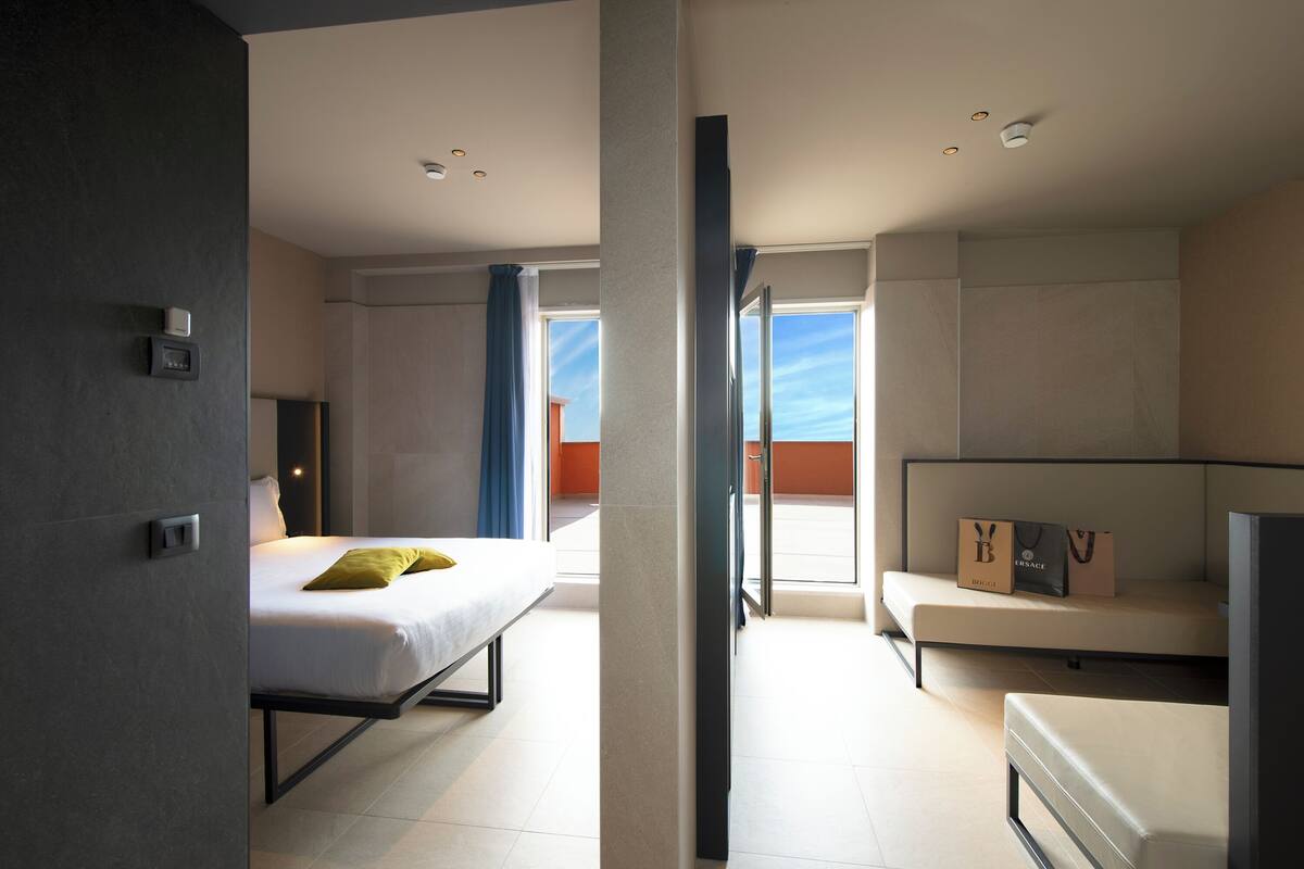 Una habitación de hotel moderna con cama, sofá y balcón con vistas.