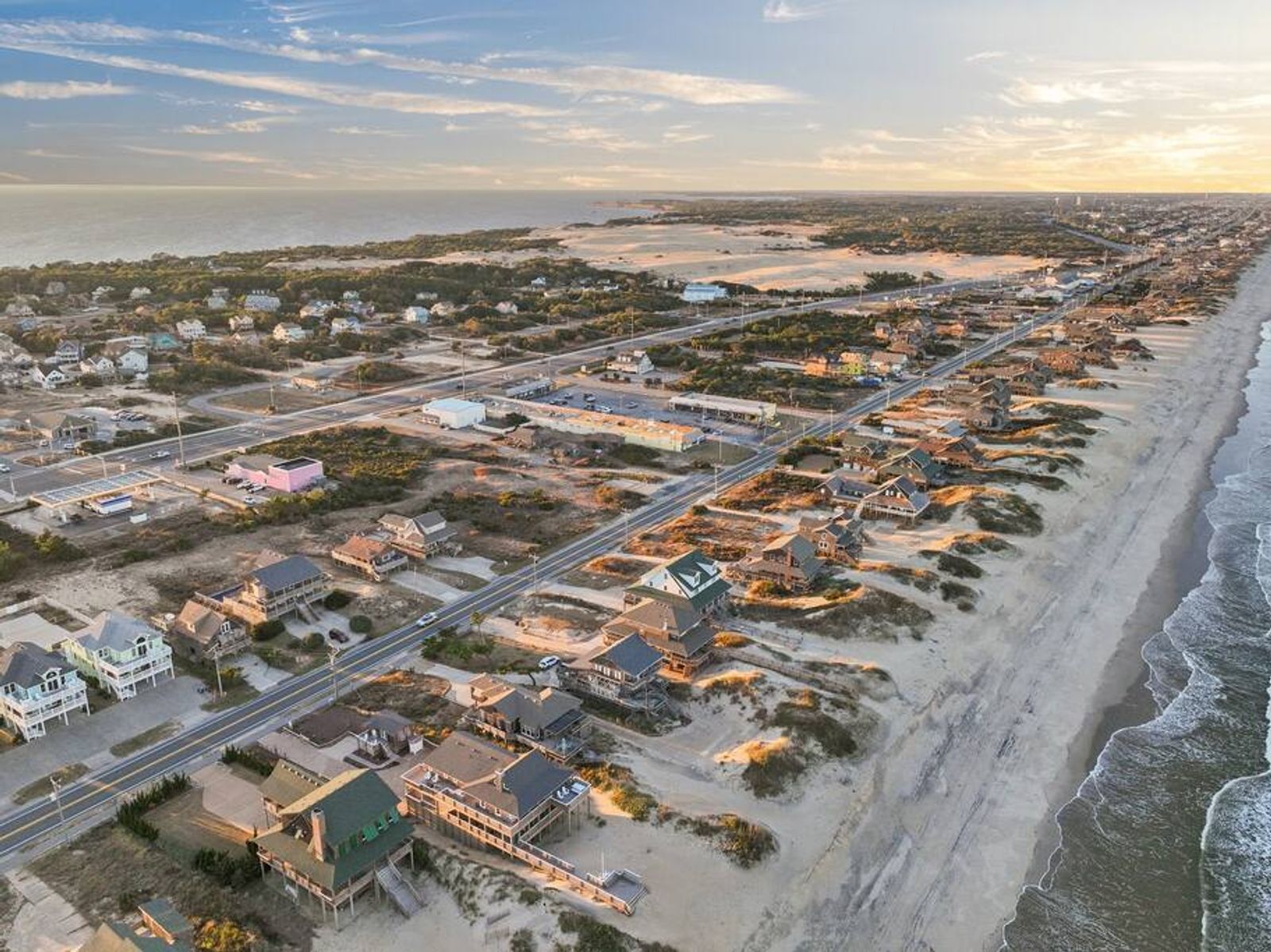 Vista aérea de una zona residencial costera con casas, calles y una playa.