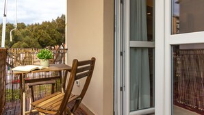 A wooden chair and table on a balcony with a view of trees and a fence. - A Casa Di Giò by TuscanyWeGo (Livorno)