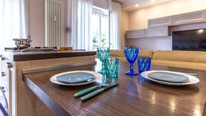 A modern kitchen with a wooden countertop, two blue glassware sets, and a dining table set for four. - A Casa Di Giò by TuscanyWeGo (Livorno)