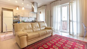 A modern kitchen with white cabinets, a beige sofa, and a red patterned rug. - A Casa Di Giò by TuscanyWeGo (Livorno)