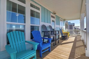Une terrasse en bois avec des fauteuils Adirondack, une table et une vue sur les gratte-ciel de la ville.