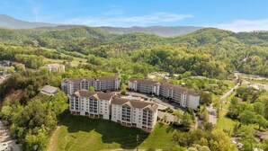 Un hôtel à plusieurs étages doté d’une cour intérieure, entouré d’une végétation luxuriante et avec des collines en arrière-plan.