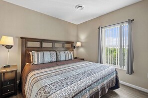 A bedroom with a large bed, two bedside tables, a window with curtains, and a view of greenery outside. - Top Floor, Scenic Mtn View, Walk-in Shower (Pigeon Forge)