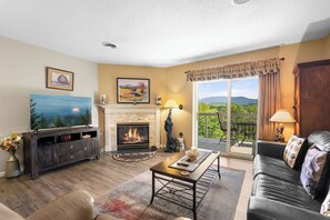 A living room with a fireplace, a television, and a sofa. - Top Floor, Scenic Mtn View, Walk-in Shower (Pigeon Forge)