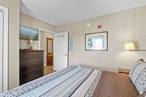 Une chambre à coucher comprenant un lit, une commode et une porte donnant sur une autre pièce.