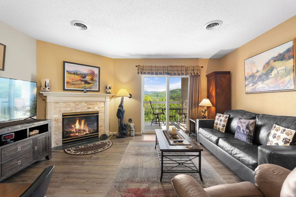 A living room with a fireplace, leather sofa, and a television.