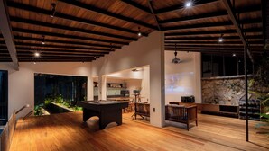 Un grand espace intérieur doté d’une table de billard, d’un plancher en bois et d’un mur en pierre.
