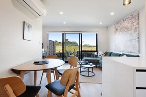 Uma sala de estar moderna com área de jantar, janelas amplas e vista para o exterior.