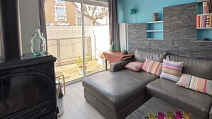 A modern living room with a black fireplace, a sofa set, a coffee table, and a bookshelf against a blue wall. - Vacation home, 300M BEACH (CABOURG town center)-6 people, 3 bedrooms (Cabourg)