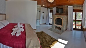 A bedroom with a red bed, a fireplace, a television, and a view of the outside. - Villaggio di Roma Suítes  (Campos do Jordao)