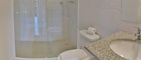 A bathroom with a glass-enclosed shower, a toilet, a sink, and a towel.