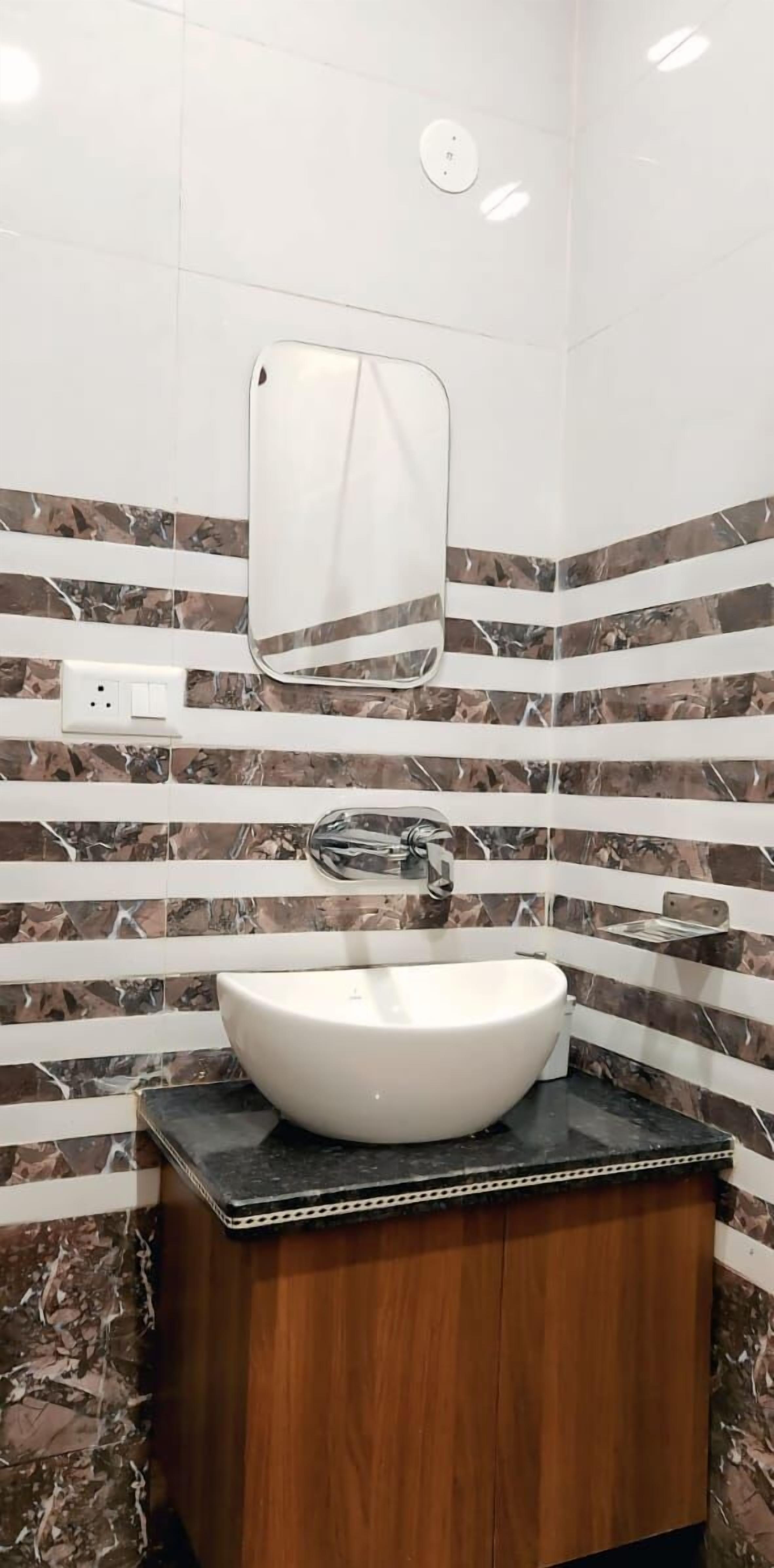Een badkamer met een witte wastafel, een houten kastje en een spiegel aan de muur.