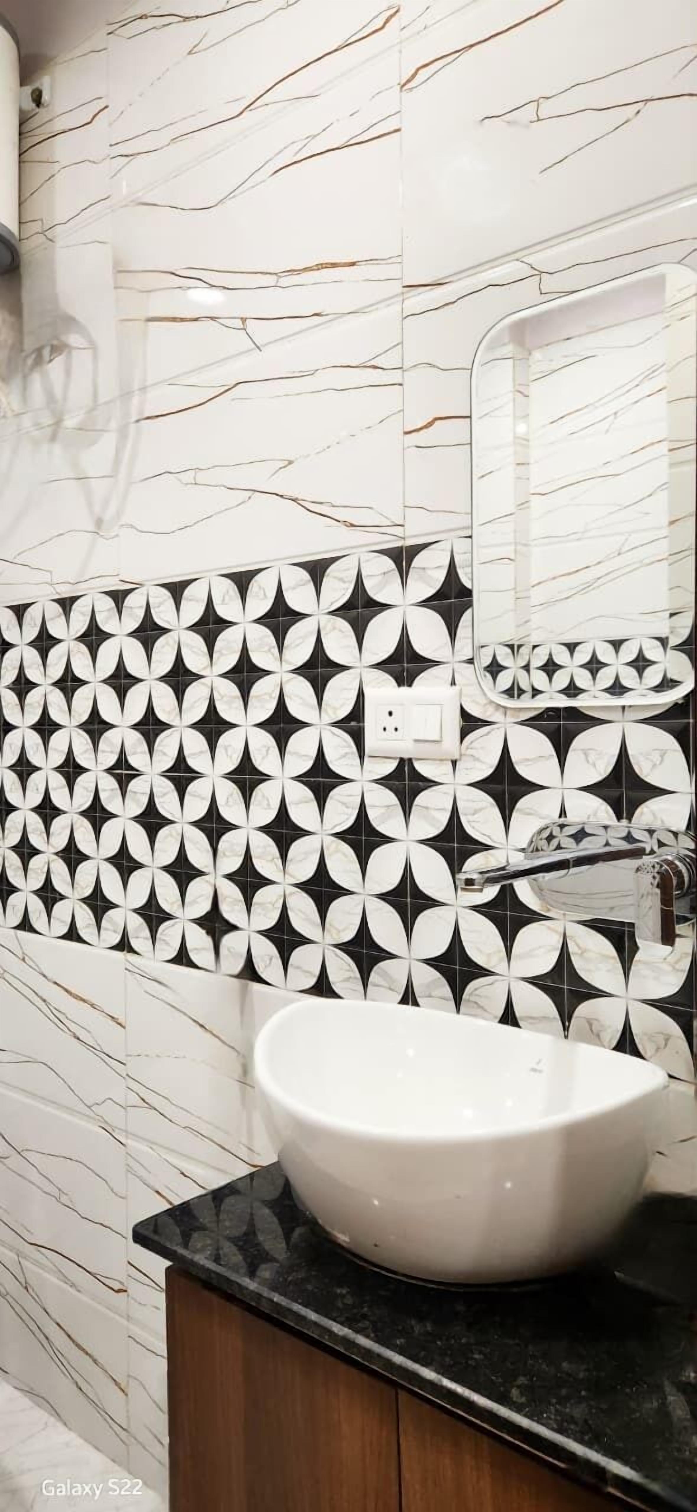 A bathroom with a white sink, black and white patterned tiles, and a marble wall.