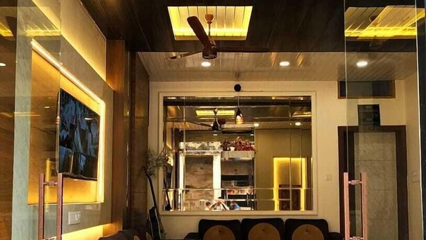A modern living room with a sofa, coffee table, and a TV mounted on the wall. - Shanti Residency (Varanasi)