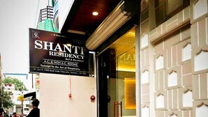 A hotel entrance with a red carpet, a signboard for 'SHANTI RESIDENCY', and a motorcycle parked outside. - Shanti Residency (Varanasi)