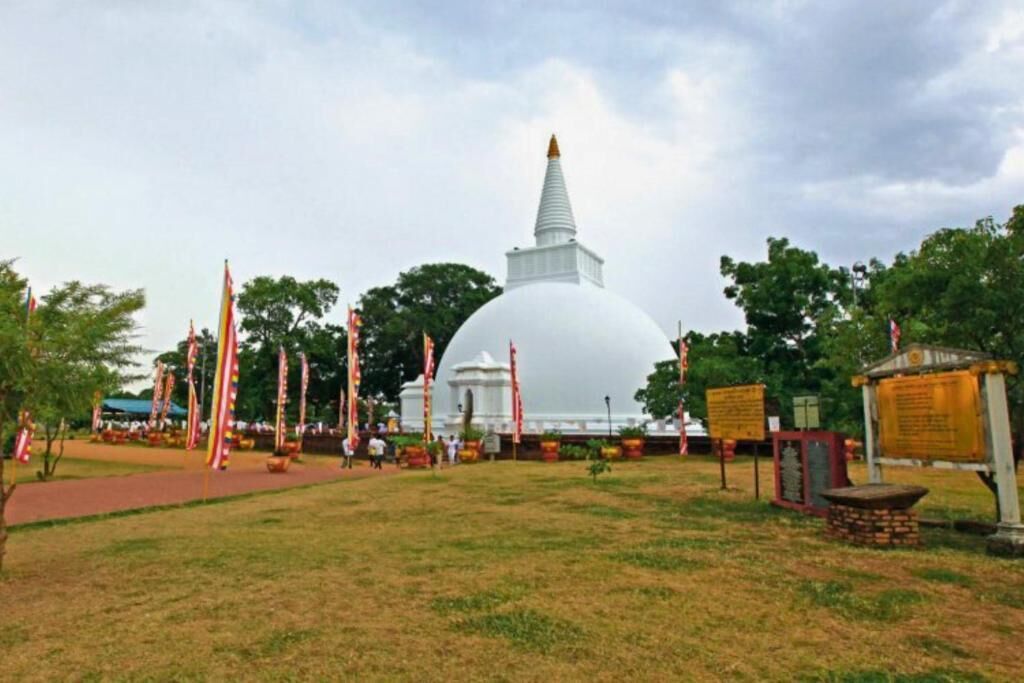 A large white dome structure with a pointed spire, surrounded by a grassy area with flags and informational signs.